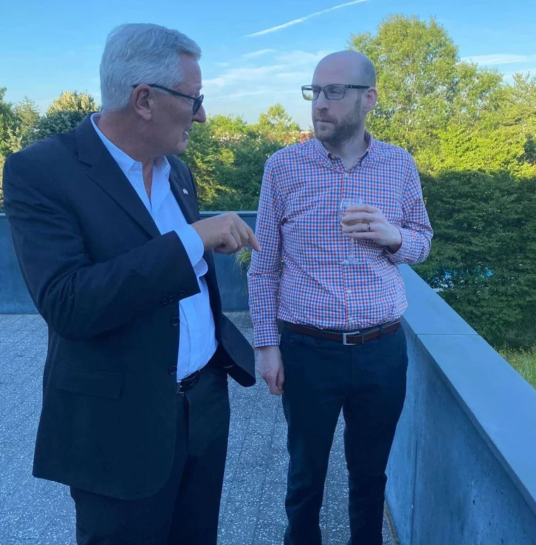 Jeffrey Dickinson in conversation with a colleague at a reception